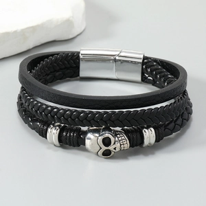 Detail of multi-layer black leather bracelet with silver skull charms and magnetic clasp