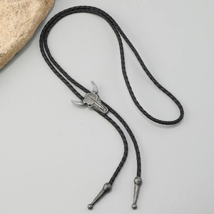 Detail of western vintage bull skull bolo tie with woven cord and silver metal tips