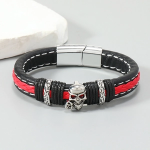 Detail of black braided leather bracelet with red stripe and silver skull and rose charm