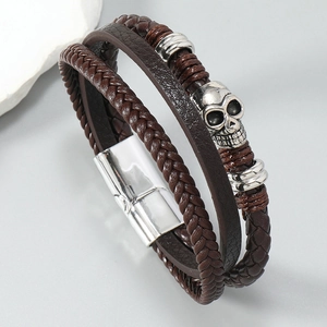 Macro detail of men's leather punk bracelet with skull charm and magnetic metal clasp