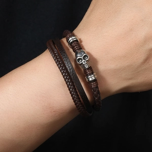 Punk woven leather bracelet with silver skull charm and magnetic clasp on male wrist