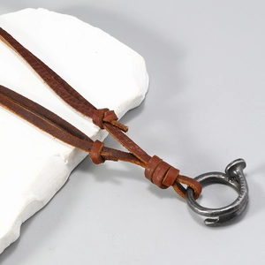 Detail of vintage brown leather necklace with a rustic metal nail ring pendant