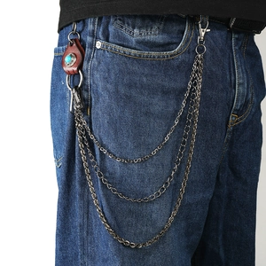 Three-layer metal wallet chain with brown leather pendant and turquoise stone on denim jeans
