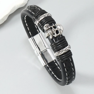 Detail view of woven leather bracelet with silver skull charm and magnetic metal clasp