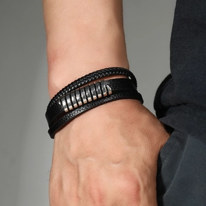 Close-up of men's multi-layer braided black leather bracelet with silver metal tubes