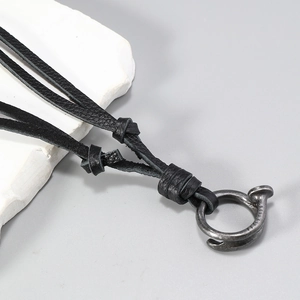 Detail of handcrafted black leather cord with vintage distressed metal ring pendant