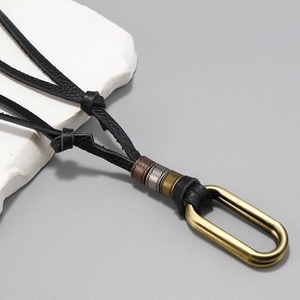 Detail of adjustable black leather cord necklace with vintage metal beads and gold oval loop