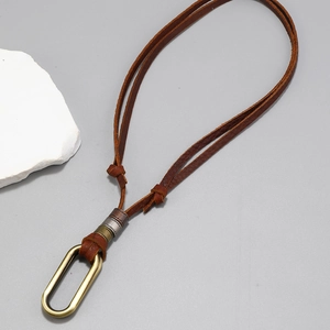 Close-up of vintage long brown leather necklace with bronze oval pendant and metallic rings