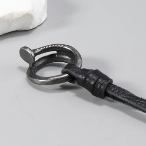 Macro detail of industrial nail pendant with antique silver finish and black leather cord