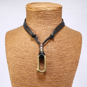 Macro detail of adjustable double-strand black leather necklace with vintage metal pendant