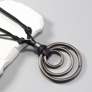 Détails d'anneaux concentriques géométriques sur un collier cordon en cuir noir mat