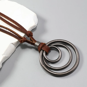 Détail de bagues métalliques vintage sur cordon en cuir marron foncé pour long collier
