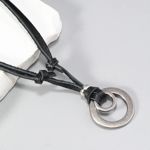 Detailed macro view of nested metal rings with matte brushed texture on leather cord