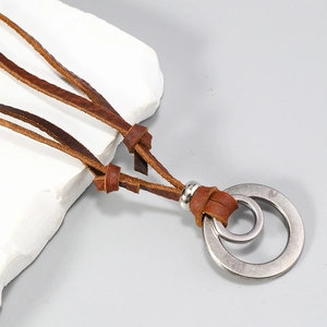 Macro shot of double interlocking metal rings on brown braided leather cord