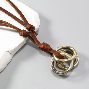 Detail of interlocking gold and silver metal rings on a dark brown leather necklace cord