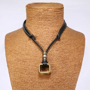 Detail of vintage double-ring pendant on black leather cord shown on a mannequin