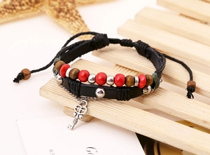 Detail of beaded multilayer leather bracelet featuring a silver heart key charm pendant