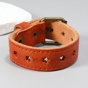 Détail macro du bracelet en cuir marron avec découpes en étoile et boucle en bronze