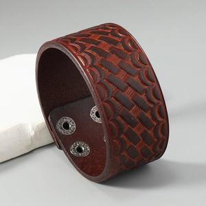 Detailed view of dark brown wide leather bracelet with braided texture and silver snaps