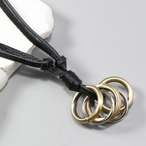 Detailed close-up of multi-layered leather cord with interlocking bronze and silver metal rings