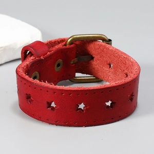 Détail macro du bracelet en cuir rouge vintage avec étoiles et boucle en bronze antique