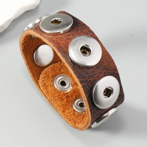 Detailed view of dark brown textured leather wide cuff bracelet with silver metal studs