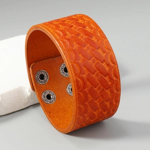 Detail of orange-brown wide leather bracelet with embossed woven texture and metal snaps