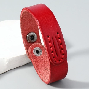 Detailed close-up of red genuine leather wristband with metal snap button and stitching
