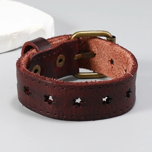 Détail macro du bracelet en cuir marron rouge avec étoiles découpées et boucle bronze