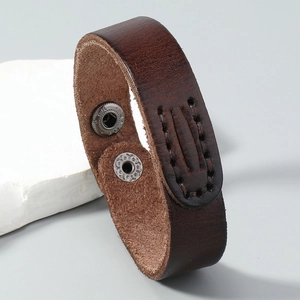 Macro shot of dark brown leather bracelet with visible stitching and adjustable snap buttons