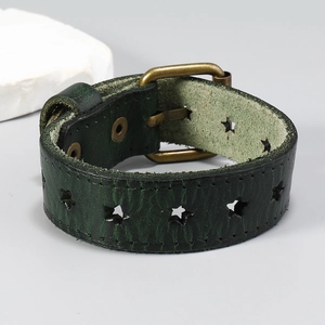 Détail macro du bracelet en cuir vert foncé avec étoile ajourée et boucle métallique