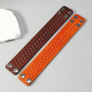 Detail view of woven pattern and bronze metal snap buttons on wide leather bracelets