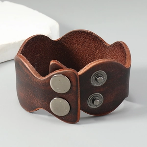 Detail of vintage dark brown wide leather bracelet with dual metallic snap buttons