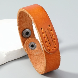 Macro detail of brown leather bracelet showing orange stitching and metal snap buttons
