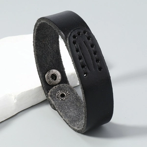 Detail of vintage black leather bracelet featuring white stitching and dual metal snap buttons
