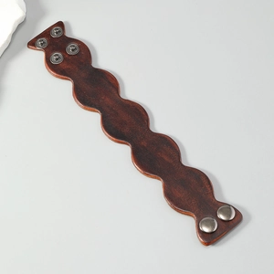 Macro view of vintage dark brown leather bracelet with scalloped edges and metal studs