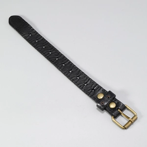 Détail d'un bracelet en cuir noir avec découpes en étoile et boucle en bronze vintage