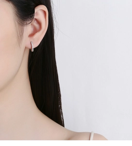Detail of 925 sterling silver hoop earrings with shimmering paved zircon on female model