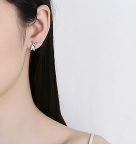 Close-up of a silver rabbit earring with a pink moonstone on a model's ear