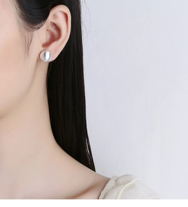 Macro detail of matte sterling silver hemispherical stud earring on model ear lobe