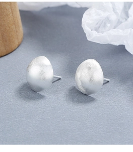 Macro detail of 925 sterling silver matte semi-spherical earrings with organic texture