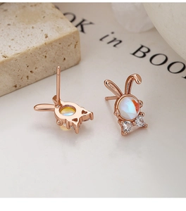 Macro detail of rose gold rabbit studs with moonstone and rhinestone bow accents