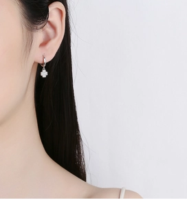 Primer plano de pendientes de aro en plata 925 con colgantes de trébol y diamantes