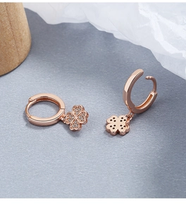 Detalle macro de pendientes de trébol en oro rosa con incrustaciones de circonitas