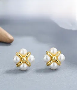 Macro detail of S925 sterling silver four-leaf clover pearl stud earrings with gold accents