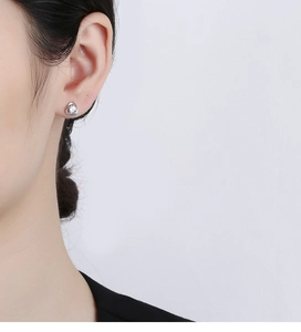 Gros plan d'un clou d'oreille trèfle en argent 925 avec zircon sur l'oreille du modèle
