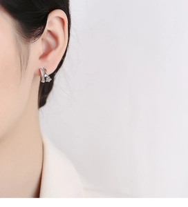 Detailed close-up of a silver 925 sterling silver star hoop earring worn by a model