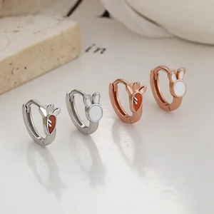 Macro detail of asymmetric 925 silver bunny and carrot hoop earrings in silver and rose gold