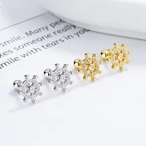 Detailed view of nautical anchor studs in gold and silver with white zircon pavé setting