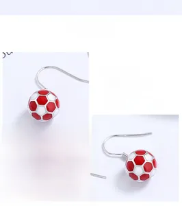 Detailed macro view of S925 silver football drop earrings with red enamel detailing